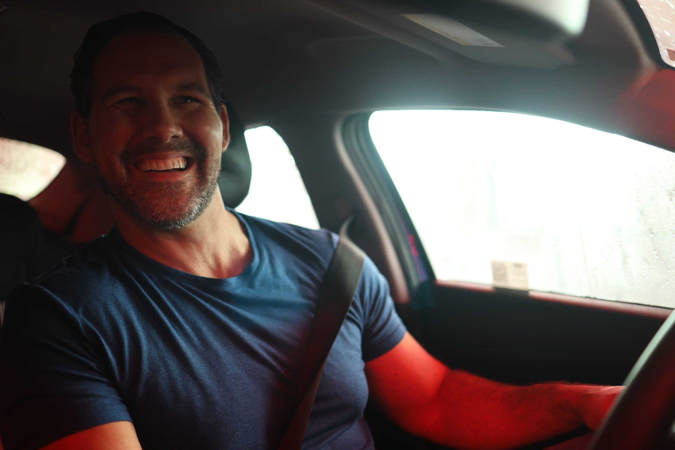 A driver smiling behind the wheel as their car moves through the Bubble Blast tunnel